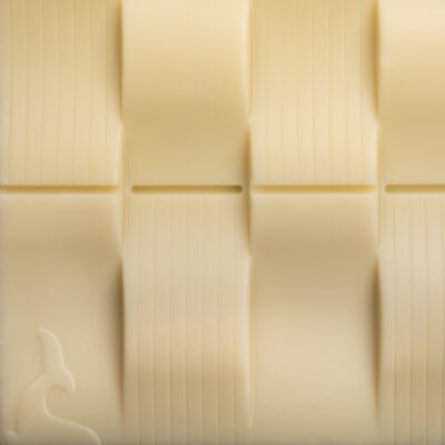 Tablette Chocolat blanc de La Baleine à Cabosse dans son emballage, posée à côté d'une tablette de chocolat blanc sans emballage