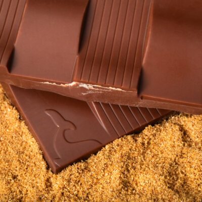 Tablette chocolat au lait 50% de cacao & bergamote de La Baleine à Cabosse dans son emballage posée à côté d'un moule en forme de tablette rempli de bergamote râpée