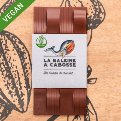 Tablette de chocolat au lait de coco 45% de cacao de La Baleine à Cabosse dans son emballage, posée à côté d'un moule en forme de tablette avec un visuel de la noix de coco