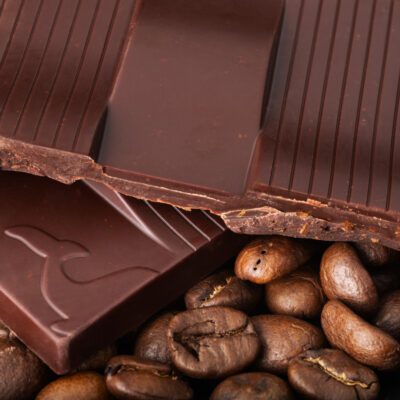 Tablette Chocolat noir 76% & brisures de café de La Baleine à Cabosse dans son emballage, posée à côté d'un moule en forme de tablette rempli de grains de café