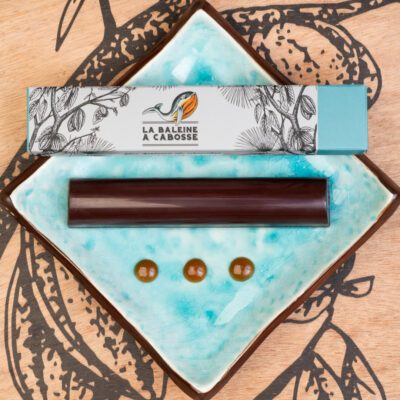 La barre fourrée d'un praliné et d'un caramel beurre salée, posée à côté de son emballage sur une assiette bleue