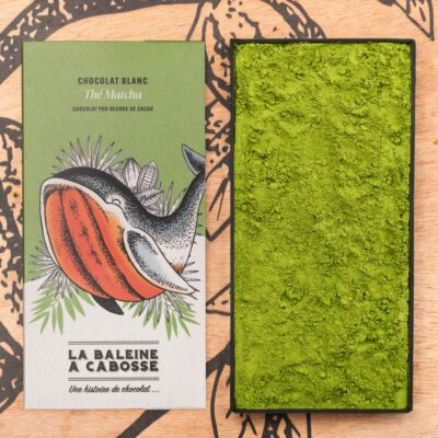 Chocolatier à Marseille - Chocolaterie artisanale La Baleine à cabosse 19 Tablette Chocolat blanc au thé matcha de La Baleine à Cabosse dans son emballage, posée à côté d'un moule en forme de tablette rempli de poudre de matcha