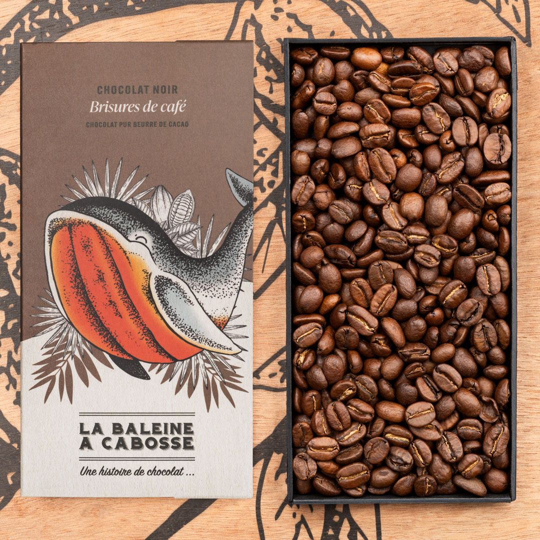 Tablette Chocolat noir 76% & brisures de café 1 Tablette Chocolat noir 76% & brisures de café de La Baleine à Cabosse dans son emballage, posée à côté d'un moule en forme de tablette rempli de grains de café