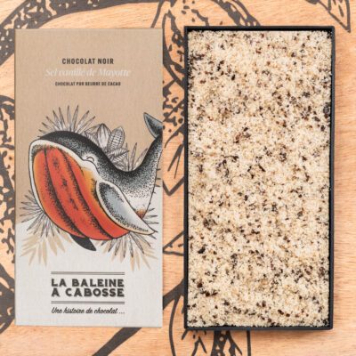 Chocolatier à Marseille - Chocolaterie artisanale La Baleine à cabosse 17 Tablette de chocolat noir 76% & sel vanillé de Mayotte de La Baleine à Cabosse dans son emballage, posée à côté d'un moule en forme de tablette rempli de sel vanillé